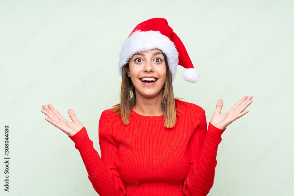 Girl with christmas hat over isolated green background with surprise facial expression Girl with christmas hat over isolated green background with surprise facial expression