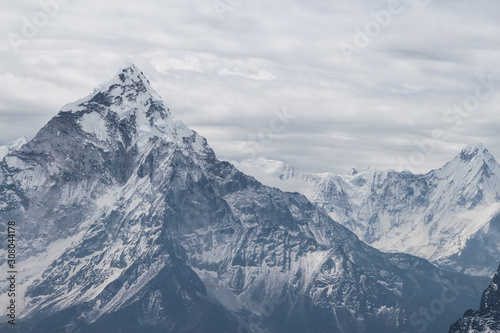 Close up view of Ama Dablam mountain peak in cloudy day near Cho La pass in Sagarmatha national park in Himalayas. Snow lumps at the very top of the mountain. Copy space.