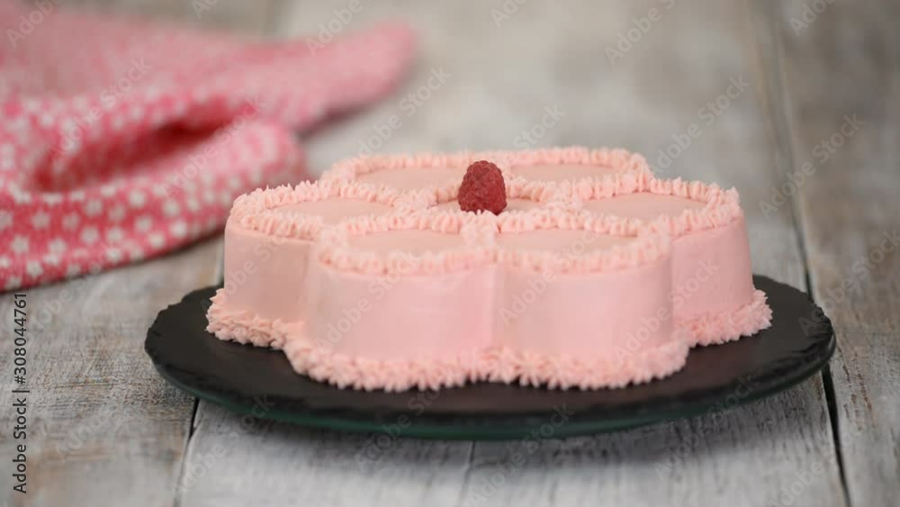 Pastry chef is decorates a pink cake in the shape of a flower with fresh raspberries. Series. Pastry chef is decorates a pink cake in the shape of a flower with fresh raspberries. Series.