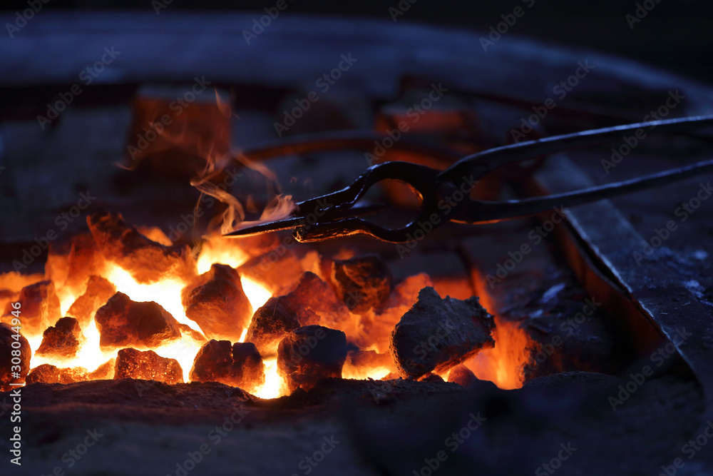 Hot coals in a furnace for heating metal for manual forging in a blacksmith workshop Hot coals in a furnace for heating metal for manual forging in a blacksmith workshop