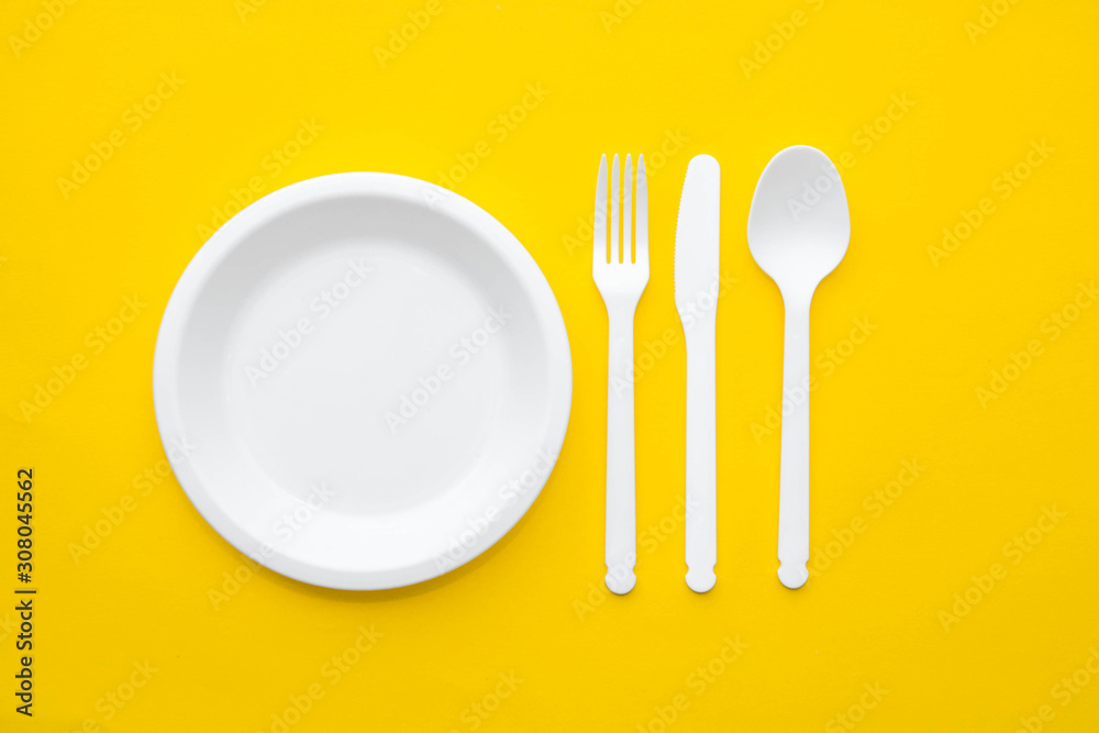 Plastic white fork, knife, spoon and plate on yellow background. Cooking utensil. Top view. Minimalist Style. Copy, empty space for text Plastic white fork, knife, spoon and plate on yellow background. Cooking utensil. Top view. Minimalist Style. Copy, empty space for text