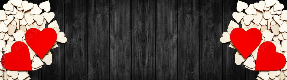 Happy Valentine's Day background panorama banner long - Wooden red and natural hearts on rustic dark black wooden texture, top view with space for text Happy Valentine's Day background panorama banner long - Wooden red and natural hearts on rustic dark black wooden texture, top view with space for text