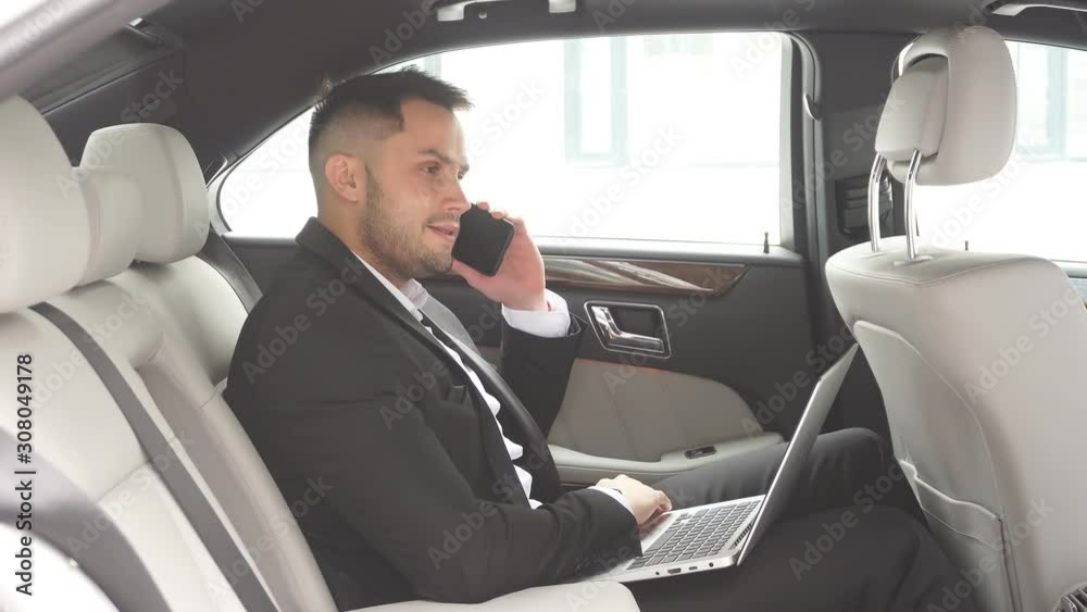 Elegant young man with beard talking on phone, process of working in car, talk with his business colleague Elegant young man with beard talking on phone, process of working in car, talk with his business colleague