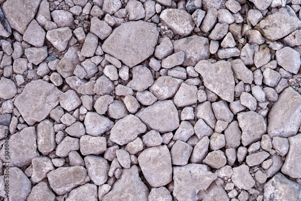 Closeup of small little grey beige blue broken crushed stones rocks lying on ground. Natural environmental background texture. Garden rubble macadam top overhead view.
