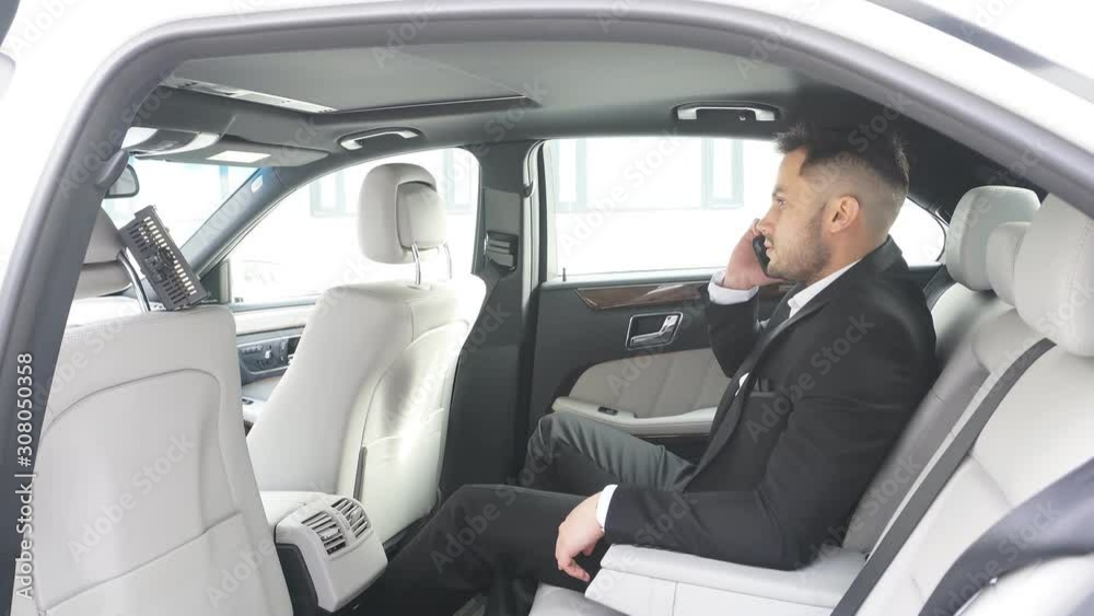 Modern caucasian man in tux sit talking with business partner, successful man with bear sit inside of executive car, good-looking business person Modern caucasian man in tux sit talking with business partner, successful man with bear sit inside of executive car, good-looking business person