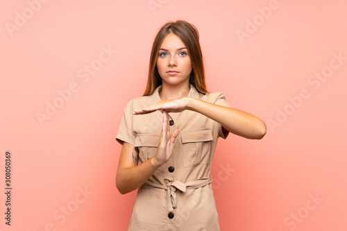Lithuanian blonde girl over isolated pink background making time out gesture © luismolinero