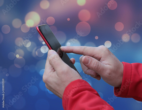 Young man holds a mobile phone with his hands .