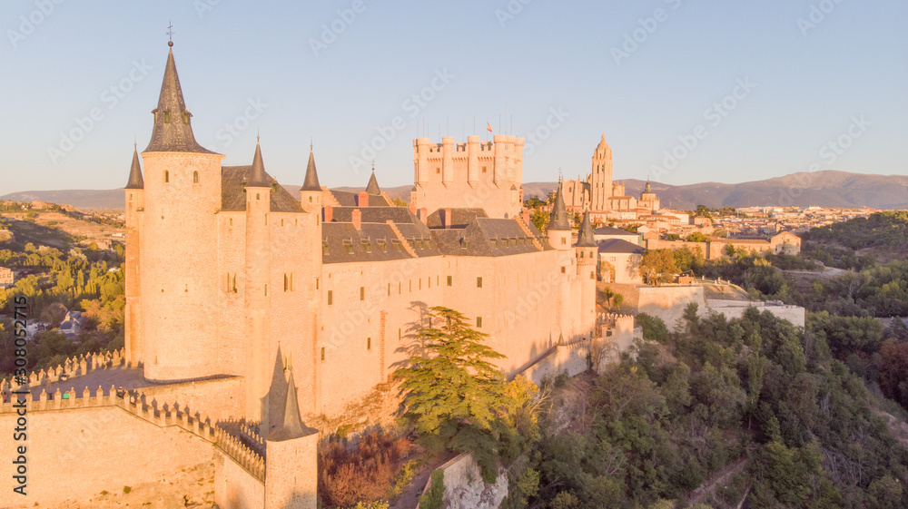 Obraz premium Historic medieval Castle in Segovia, Spain. Drone aerial view with sunset light of spanish stronghold in old town with monument cathedral. History prison, alcazar of Segovia, world heritage.