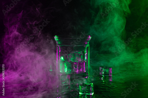 A glass with ice cubes in colourful smoke