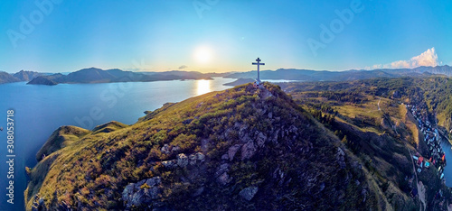 Beautiful futuristic panoramic aerial drone view to summer recreation facilities on the banks of the Bukhtarma reservoir on the Irtysh river with an Orthodox cross on top of mountain, East Kazakhstan photo