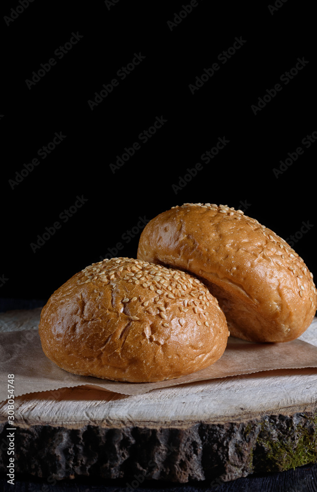 ready-made buns with sesame seeds for a hamburger on a black background