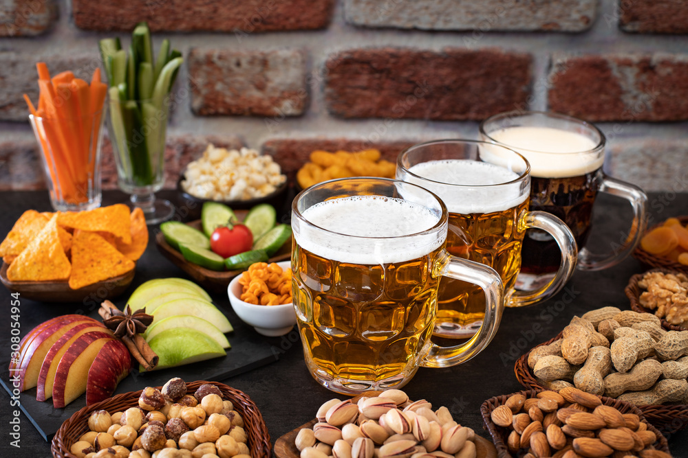 Beer glasses and beer bottles with appetizer on the table like almonds Beer glasses and beer bottles with appetizer on the table like almonds