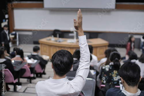Handsome Asia Student  Listening to a Lecture at the University, He Raises Hand and Asks Lecturer a Question. students a question at the elementary school