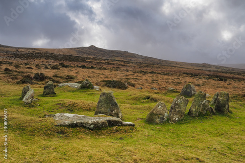 Nine Maidens Bronze Age megalithic cairn circle under Belstone Tor with dark brooding stormy sky, Dartmoor National Park, Devon, UK