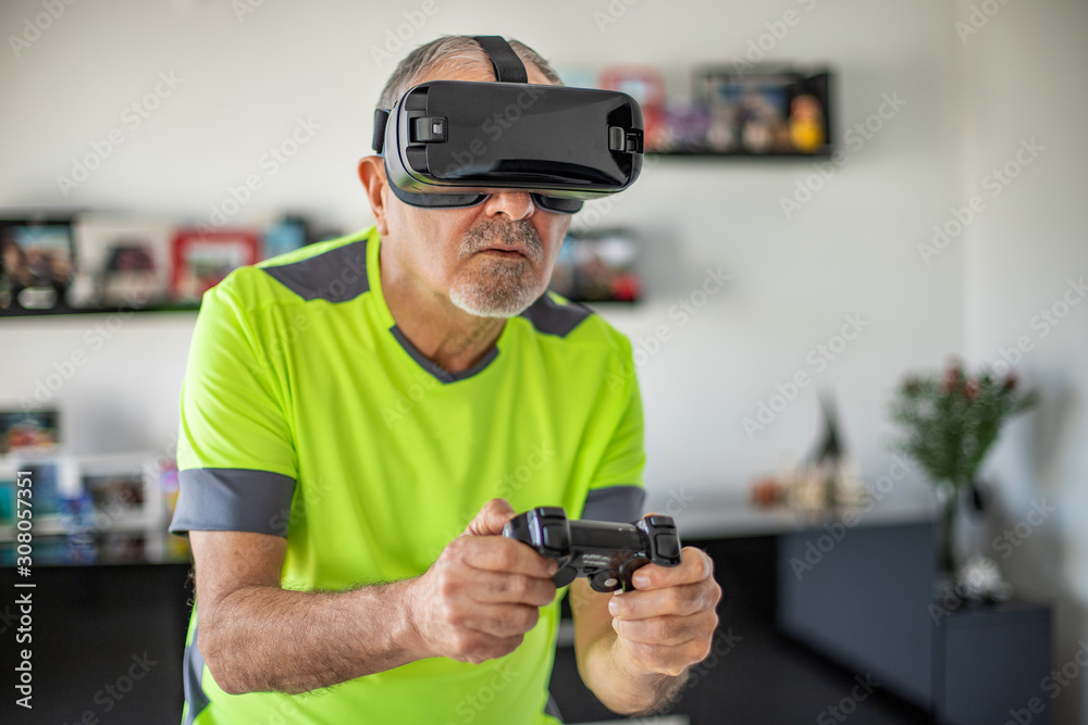 An elderly man plays video football game with virtual reality goggles and joystick An elderly man plays video football game with virtual reality goggles and joystick
