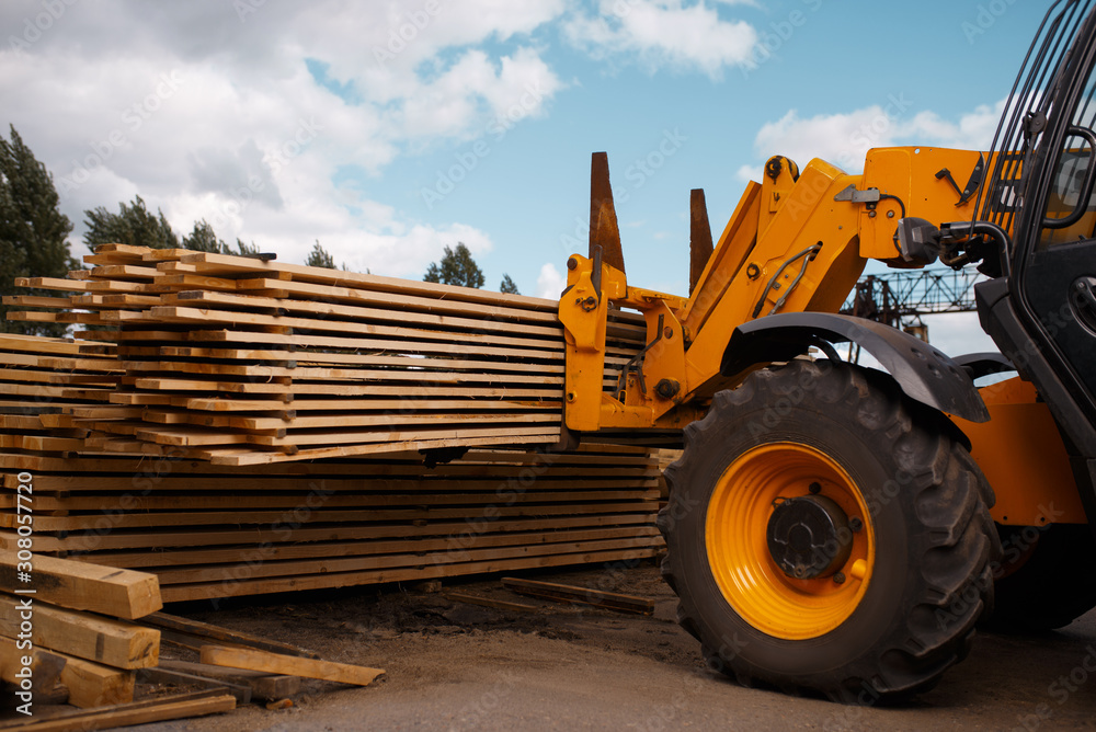 Forklift loads the boards in the lumber yard Forklift loads the boards in the lumber yard