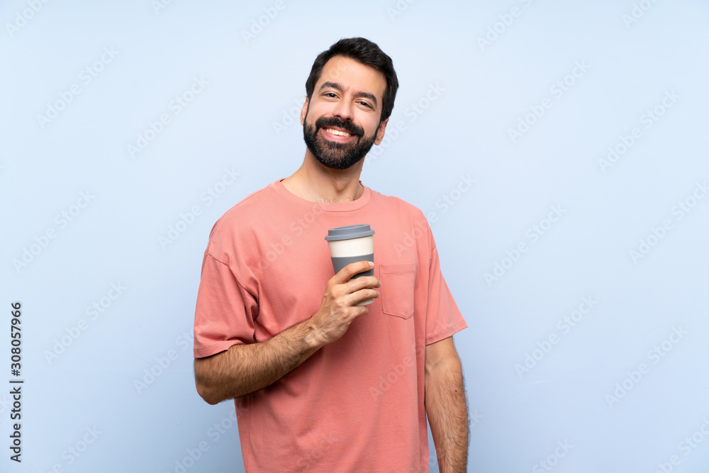 Young man with beard holding a take away coffee over isolated blue background laughing Young man with beard holding a take away coffee over isolated blue background laughing