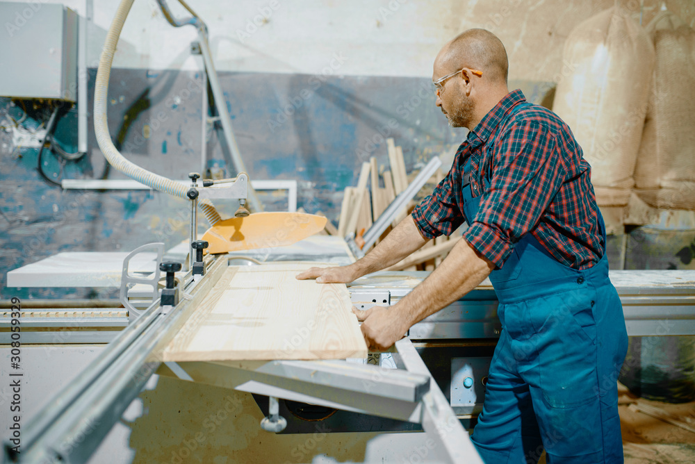 Carpenter cuts wooden board on circular saw