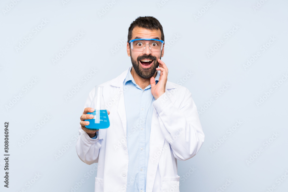 Young scientific holding laboratory flask over isolated background with surprise and shocked facial expression Young scientific holding laboratory flask over isolated background with surprise and shocked facial expression