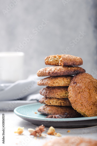 Homemade organic oatmeal cookies with peanuts  and bottle of milk on light concrete background.