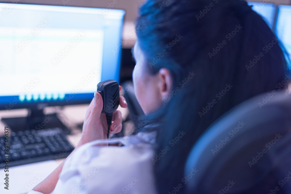 Security guard monitoring modern CCTV cameras in surveillance room. Female security guard in surveillance room. Female security guard holding portable radio in hand at workplace. Security guard monitoring modern CCTV cameras in surveillance room. Female security guard in surveillance room. Female security guard holding portable radio in hand at workplace.
