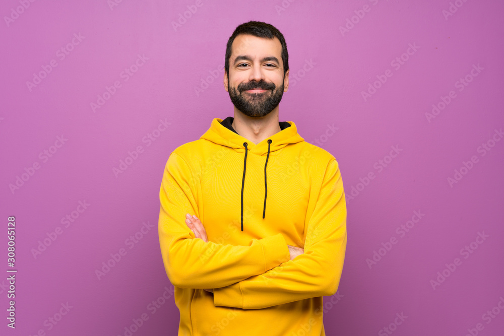 Handsome man with yellow sweatshirt keeping the arms crossed in frontal position Handsome man with yellow sweatshirt keeping the arms crossed in frontal position