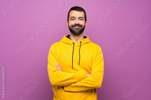 Handsome man with yellow sweatshirt keeping the arms crossed in frontal position