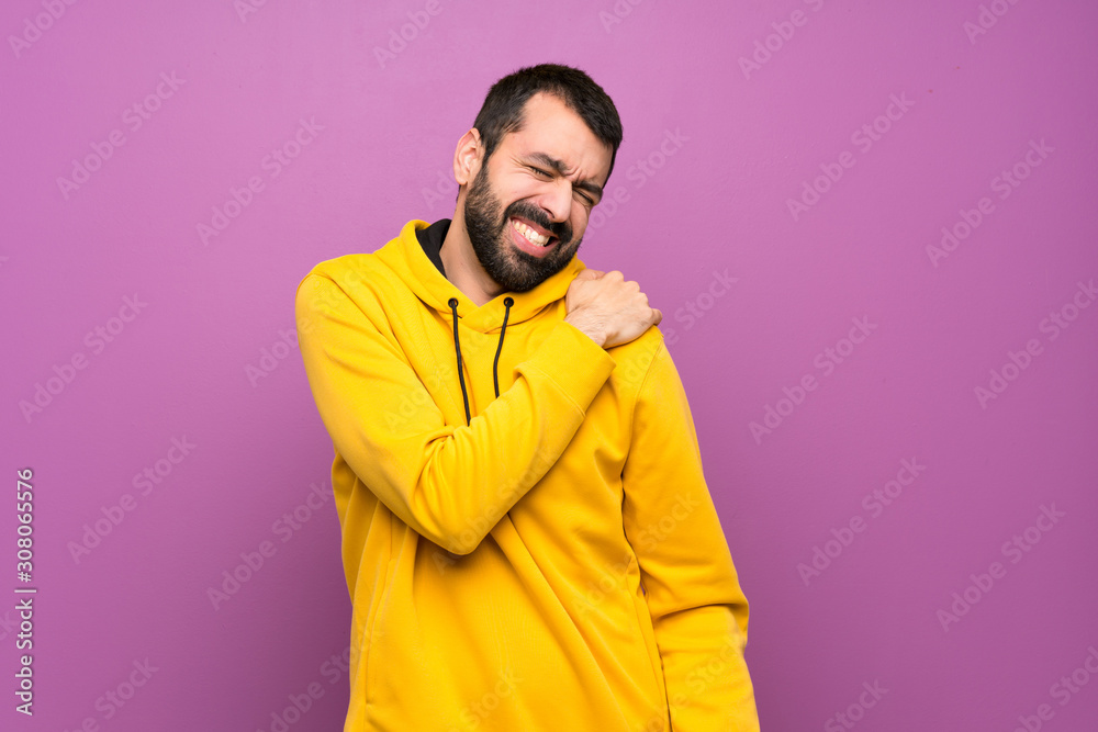 Handsome man with yellow sweatshirt suffering from pain in shoulder for having made an effort Handsome man with yellow sweatshirt suffering from pain in shoulder for having made an effort