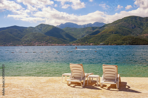 Summer vacation. Beautiful sunny landscape with two chaise lounges on beach. Montenegro, Adriatic Sea, view of Bay of Kotor near Tivat city