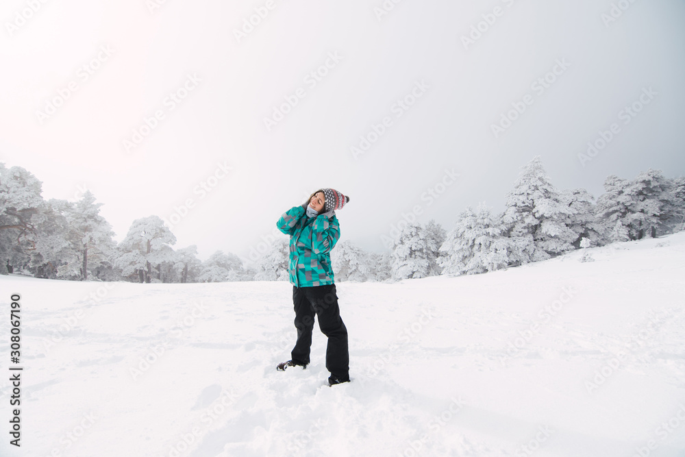 Young woman skiing in snow forest with blue winter coat