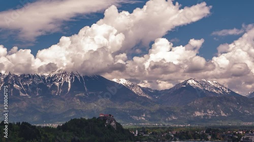 Time lapse slow moving clouds over Slovenia Alps mountains with Bled castle in foreground photo