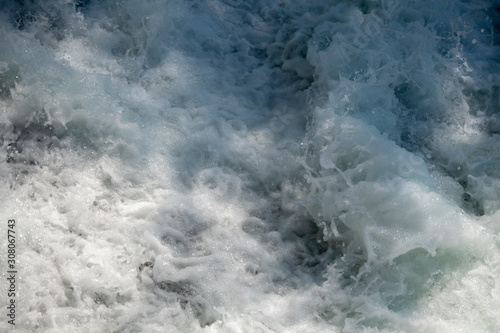 Closeup of flowing water and spray in river with sunlight for background  copy space and wallpaper
