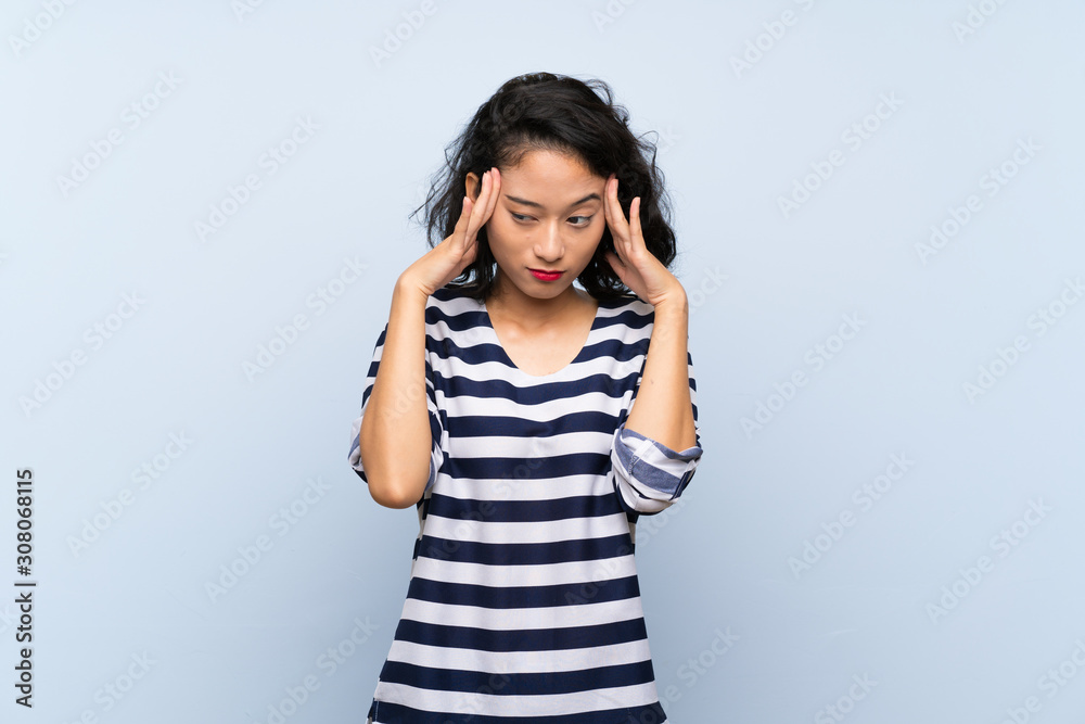 Asian young woman over isolated blue background with headache Asian young woman over isolated blue background with headache