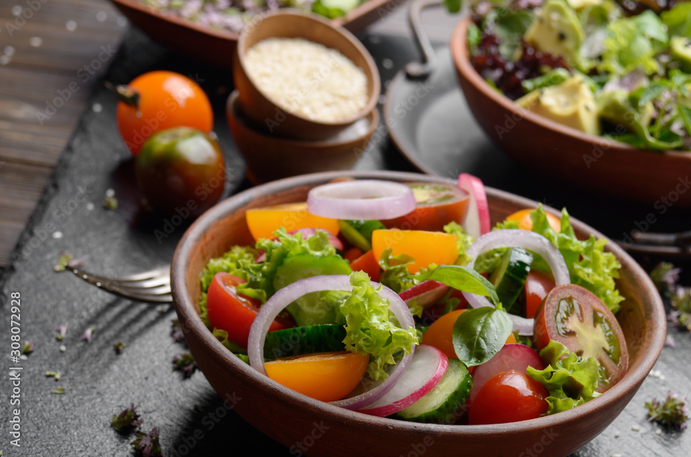 Vegetable salad of lettuce, cherry tomatoes, radish, cucumber, onion and basil on slate stone tray Vegetable salad of lettuce, cherry tomatoes, radish, cucumber, onion and basil on slate stone tray
