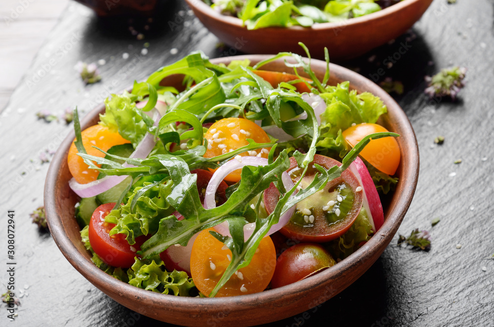 Vegetable salad of lettuce, cherry tomatoes, radish, cucumber, onion and basil on slate tray