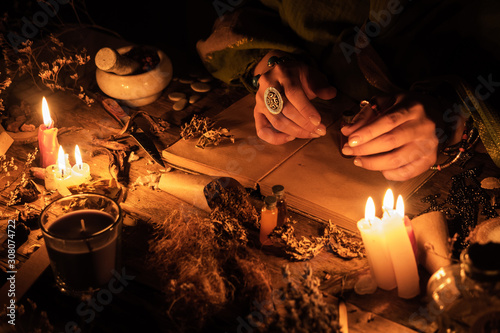 Hands fortune teller over an ancient table with herbs and books. Manifestation of occultism in the form of divination photo