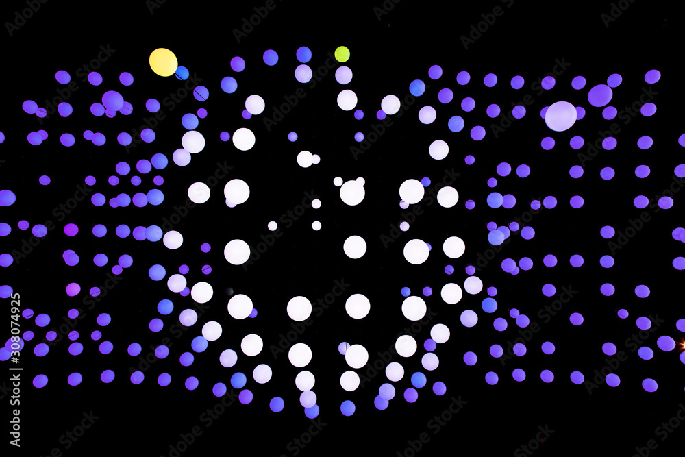 Dark purple balls on a black background, the central part of the picture is sold with white balls. Abstract glowing balls in the air. Many balls of different shapes on a black background