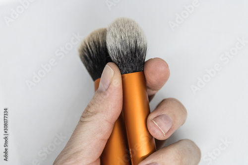 Woman hand holding a contour and buffing brushes, makeup brush closeup on the white background- Image