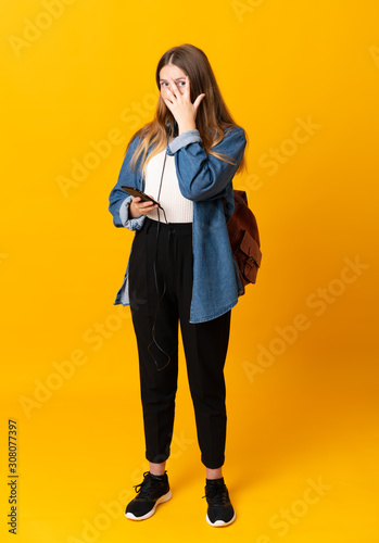 Student ukrainian teenager girl over isolated yellow background covering eyes and looking through fingers © luismolinero