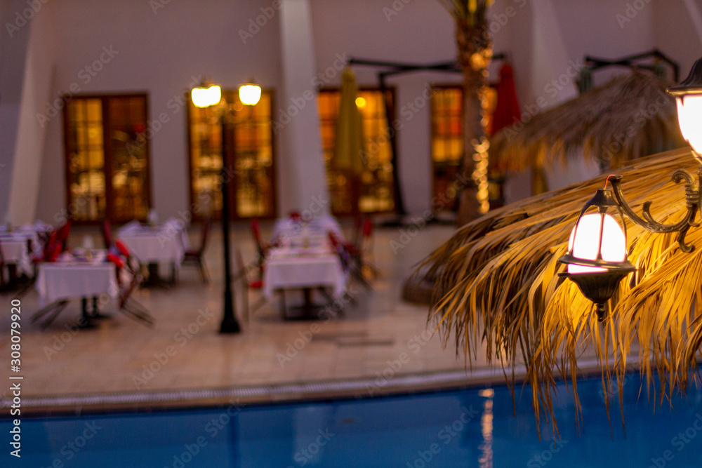 The restaurant by the pool is ready for dinner with white tablecloths and red velvet chairs.