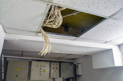 There are many cables over the False Ceiling. Interweaving of electrical wires hangs from a broken suspended ceiling. Emergency electrical wiring is on the technical floor.