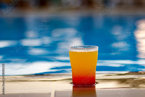 Colorful cocktail on the edge of a bright blue pool.