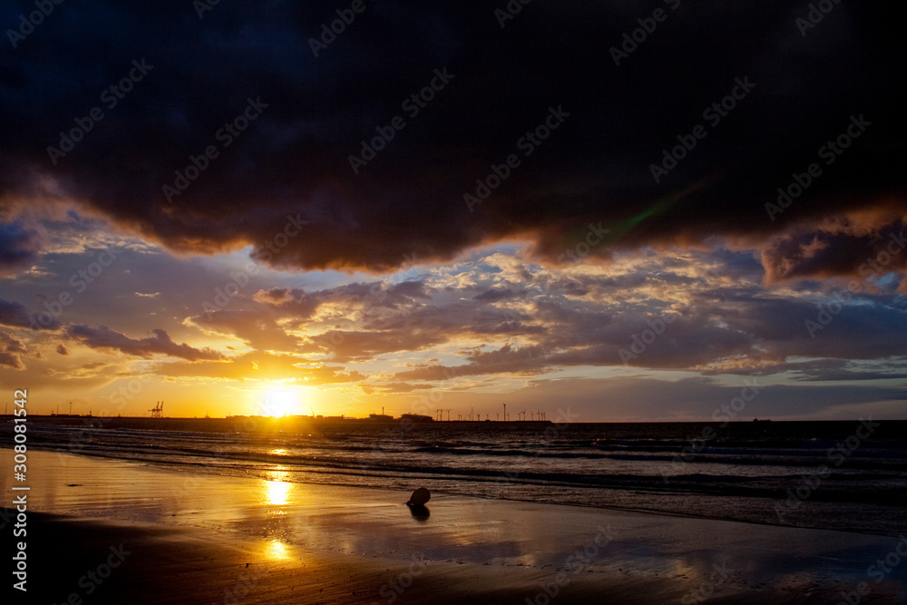 Obraz premium Reflecting sunset on a sandy beach.