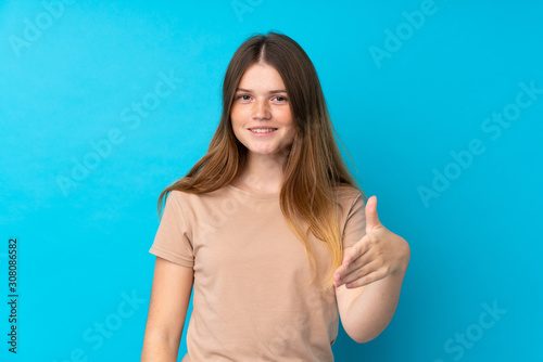 Ukrainian teenager girl over isolated blue background shaking hands for closing a good deal
