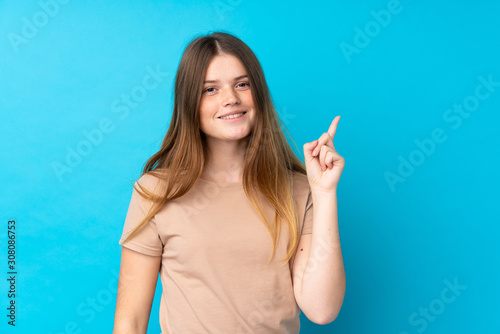 Ukrainian teenager girl over isolated blue background showing and lifting a finger in sign of the best