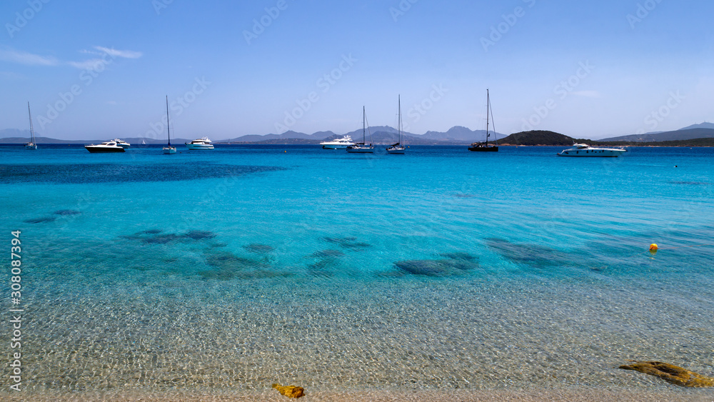 Sardinia, Italy, holidays. Sea with crystal clear azure water, yachts and ships in the sea, mountains in the background. Calm and tranquility.
