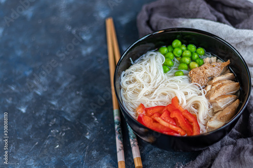 Rice noodles with beef in a clear soup (fo bo). Garnished with slices of sweet pepper, chili pepper. Asian food, healthy food concept. Copy space.   photo