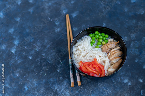 Rice noodles with beef in a clear soup (fo bo). Garnished with slices of sweet pepper, chili pepper. Asian food, healthy food concept. Copy space.   photo