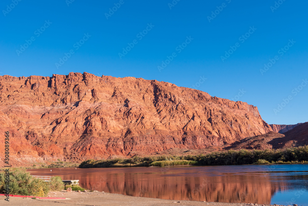 Landscape of barren pink stone hillside and the Colorado River at Lees Ferry in Glen Canyon National Recreation Area in Arizona