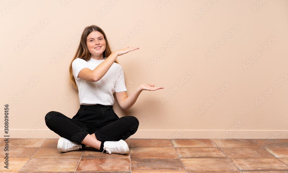 Ukrainian teenager girl sitting on the floor holding copyspace to insert an ad Ukrainian teenager girl sitting on the floor holding copyspace to insert an ad